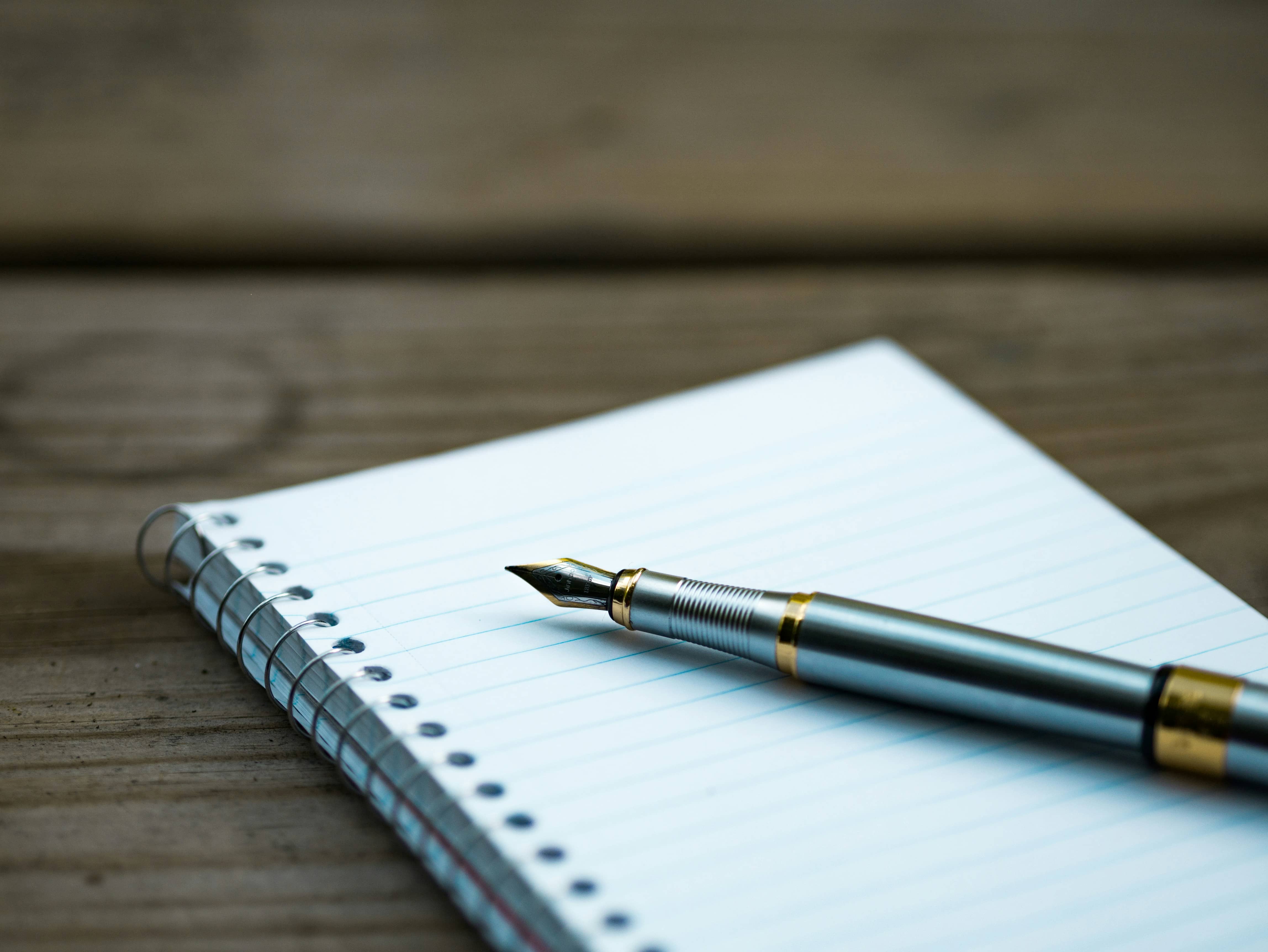 A pen resting on blank writing paper, waiting for a legacy letter to begin