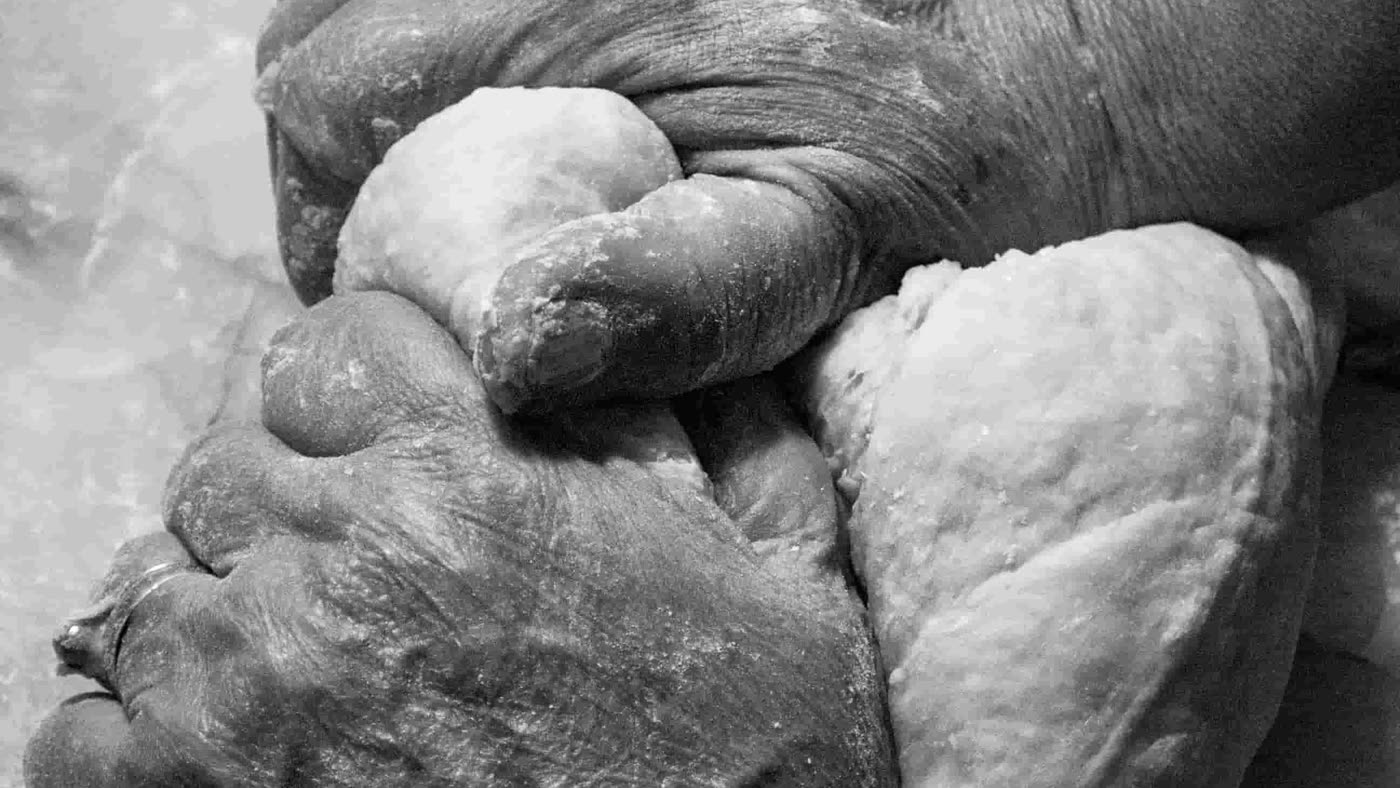 An older woman's hands kneading dough